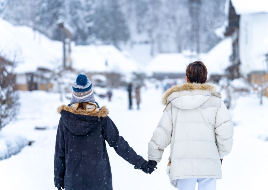 Couple se tenant la main et marchant dans le village d'Ouchi-juku en hiver