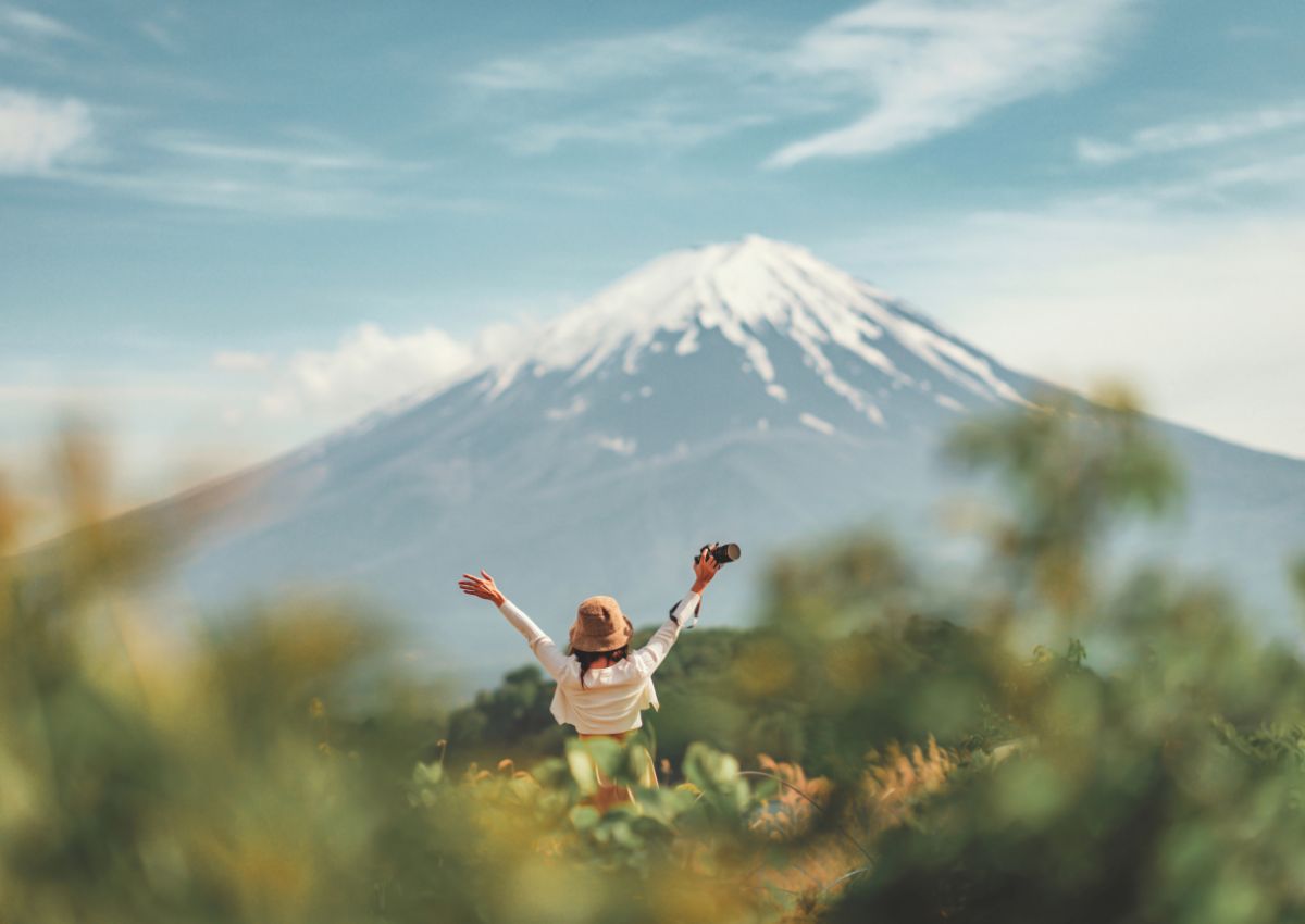 Femme tenant un appareil photo dans la végétation face au mont Fuji en été, Japon