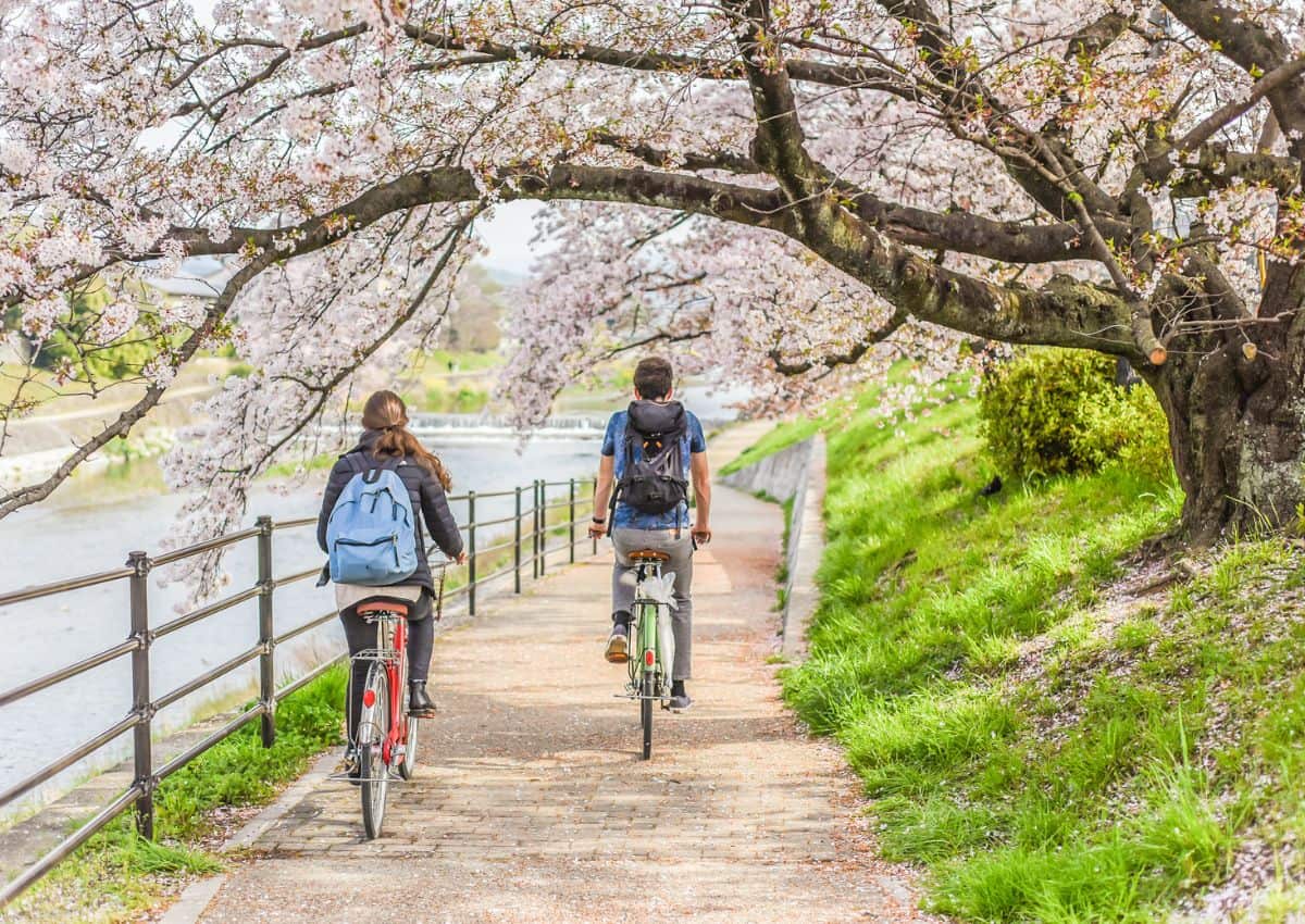 Couple à vélo au bord d'une rivière à Kyoto