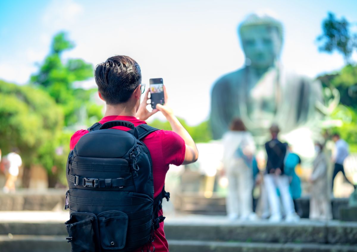 Touriste avec un sac à dos prenant le grand bouddha en photo à Kamakura, Japon