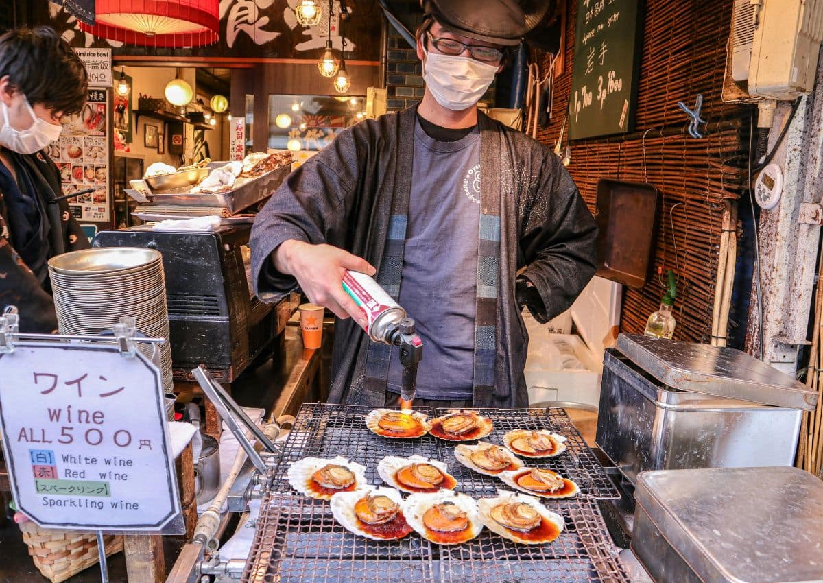 Chef préparant des coquilles Saint Jacques au barbecue dans un stand de street food à Osaka