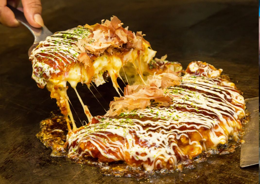 Crêpe japonaise salée à base de chou appelée okonomiyaki et grillée sur une plaque chaude