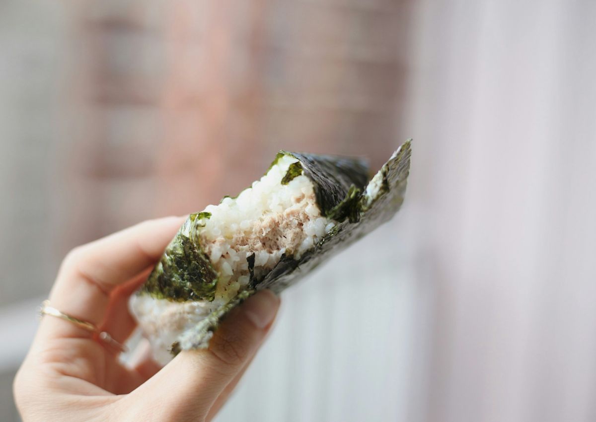 Main tenant un onigiri entamé devant l’objectif