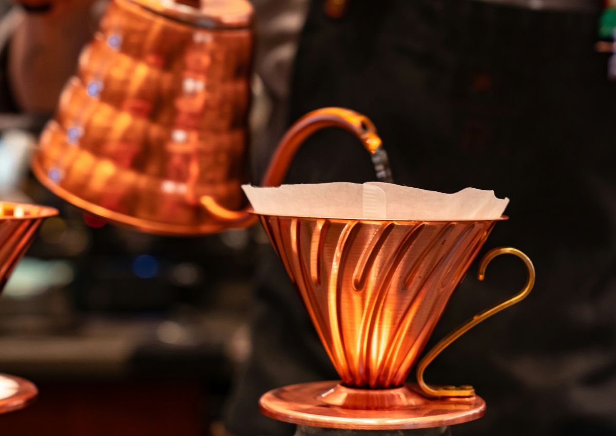 Barista préparant un café filtre avec une bouilloire en cuivre