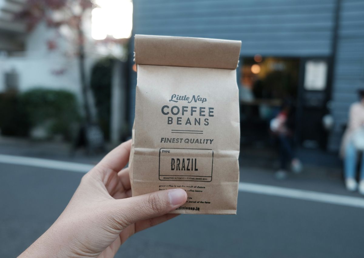 Paquet de café en grains Little Nap Coffee Stand tenu par une main dans la rue, Tokyo, Japon