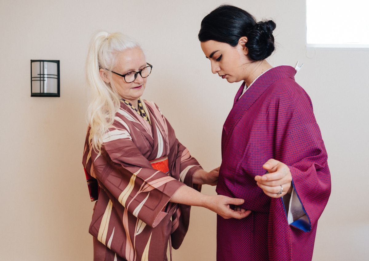 Une instructrice aide une femme à enfiler un kimono