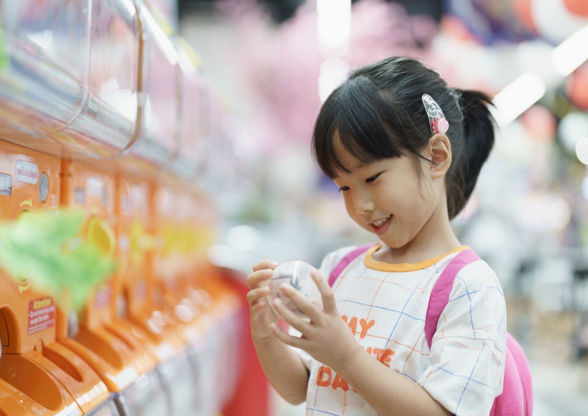 Fillette devant un distributeur japonais de jouets gacha