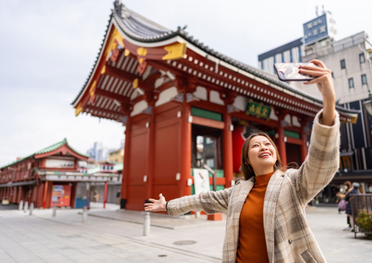 Jeune femme seule se prenant en photo devant le temple Sensoji à Asakusa, Tokyo, Japon