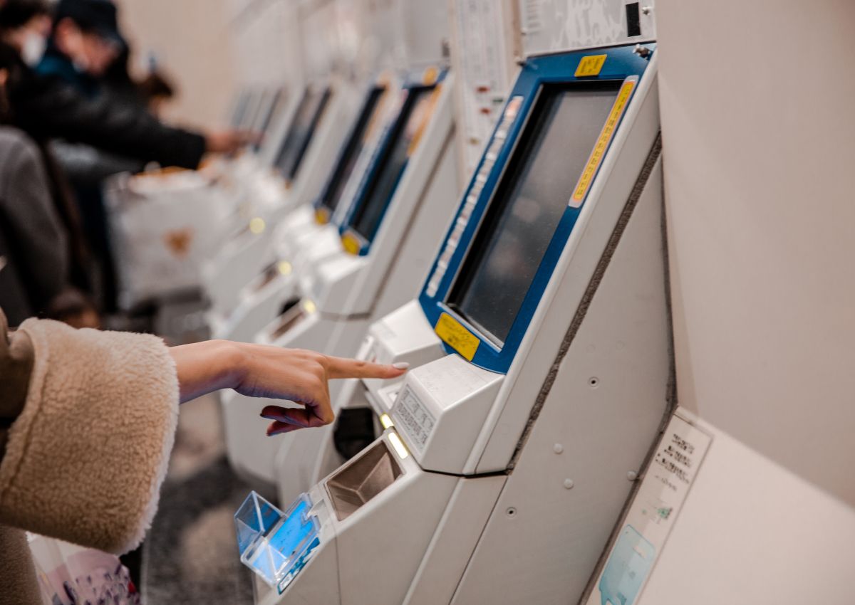 Femme achetant un ticket à une borne automatique, Japon
