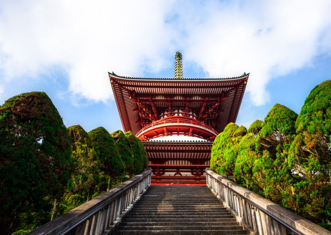 Escalier menant à une pagode majestueuse du temple Naritasan Shinshoji entourée de cyprès japonais.
