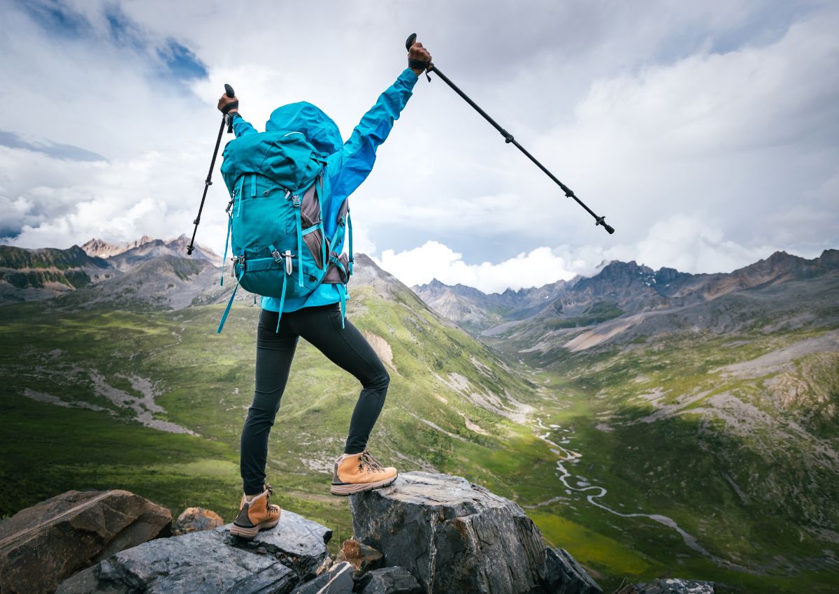 Randonneuse avec un sac à dos et des bâtons de marche au sommet d'une montagne à haute altitude