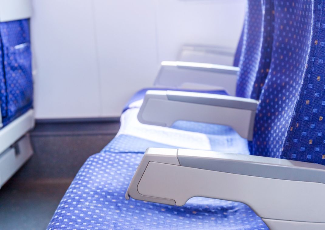 Rangée de sièges bleus inclinables à l’intérieur d’un train Shinkansen, vue sur l’accoudoir et l’allée.
