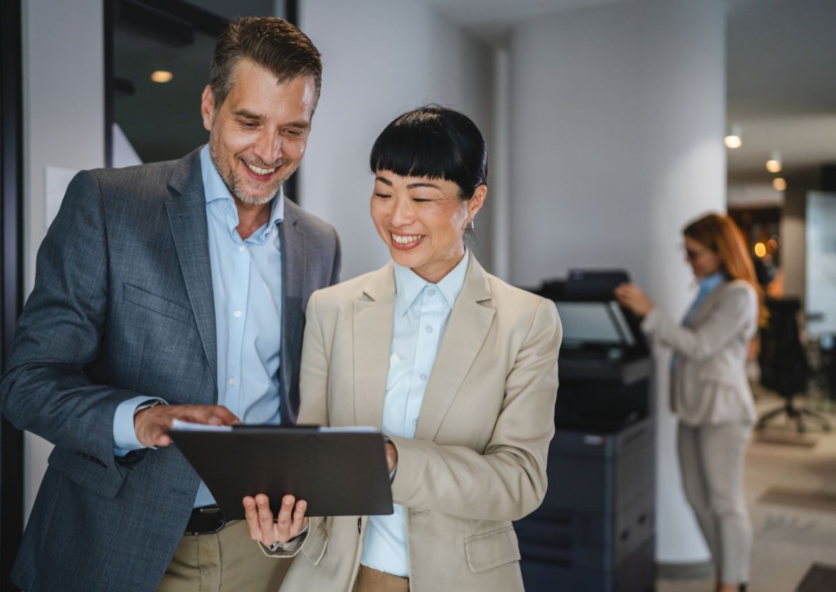Femme d’affaires japonaise et homme d’affaires occidental consultant ensemble un document sur une tablette