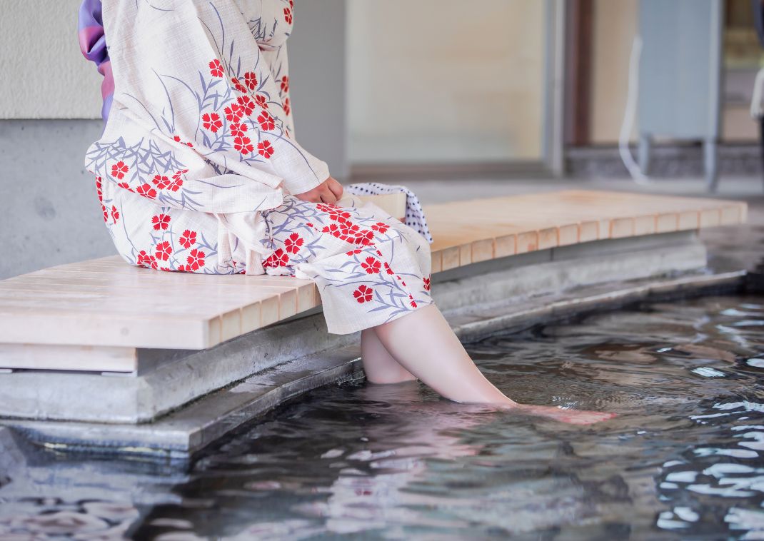 Jeune femme en yukata profitant d'un bain de pied fumant au Japon