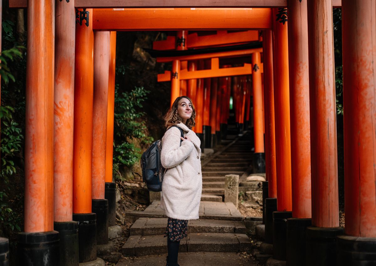 Femme dans le tunnel de torii du sanctuaire Fushimi Inari, à Kyoto, Japon