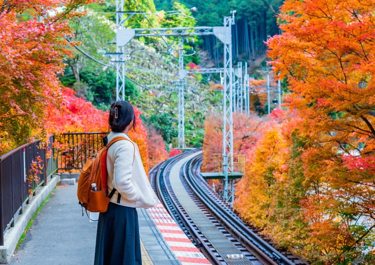 Jeune femme seule sur le quai d’une gare japonaise en automne