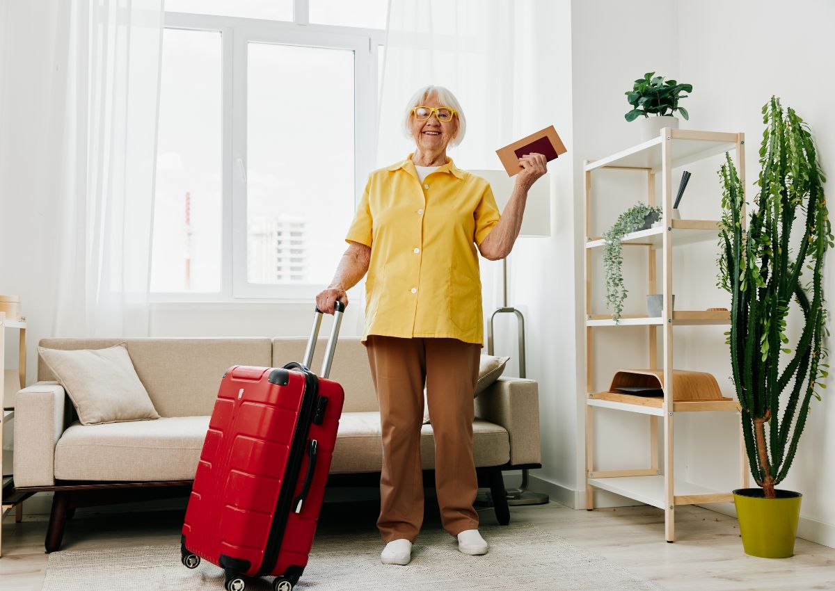 Senior avec une valise rouge et son passeport, prête à partir au Japon