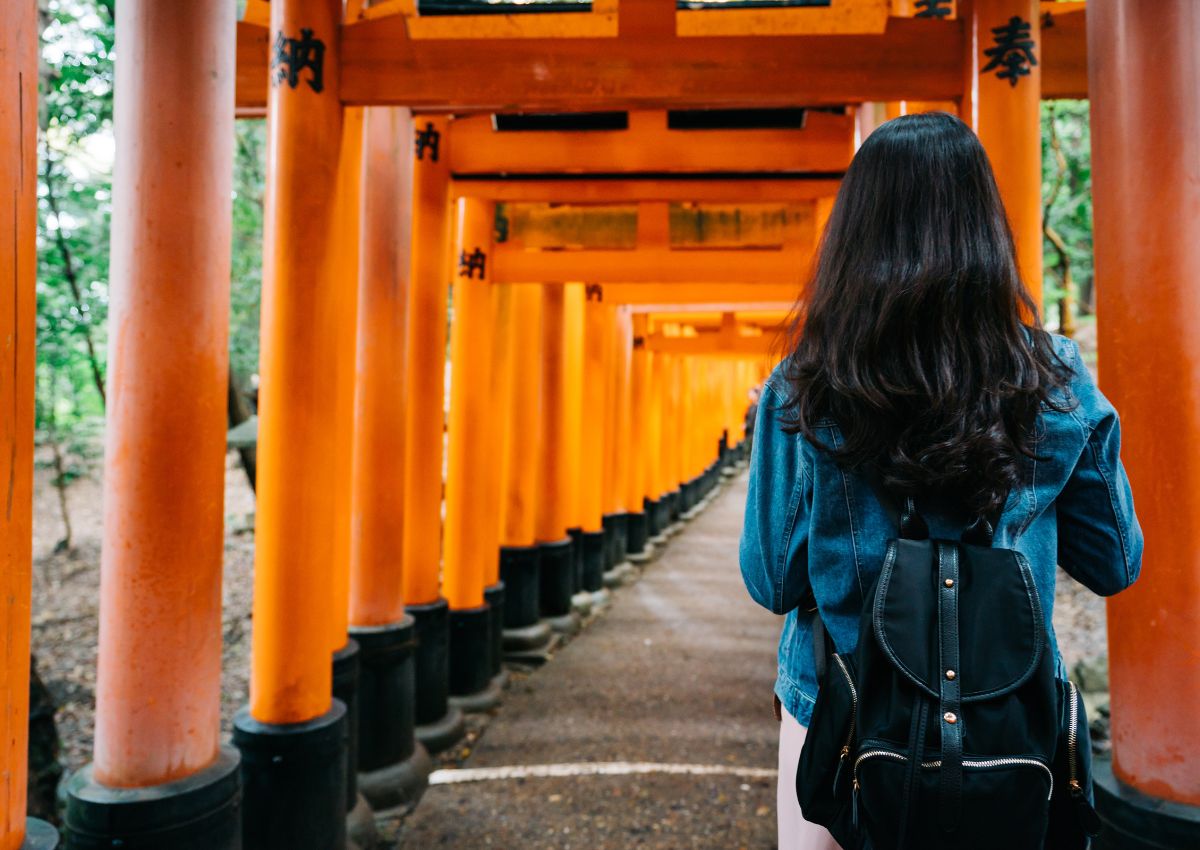Femme de dos dans le tunnel de torii rouges du sanctuaire Fushimi Inari, Kyoto, Japon
