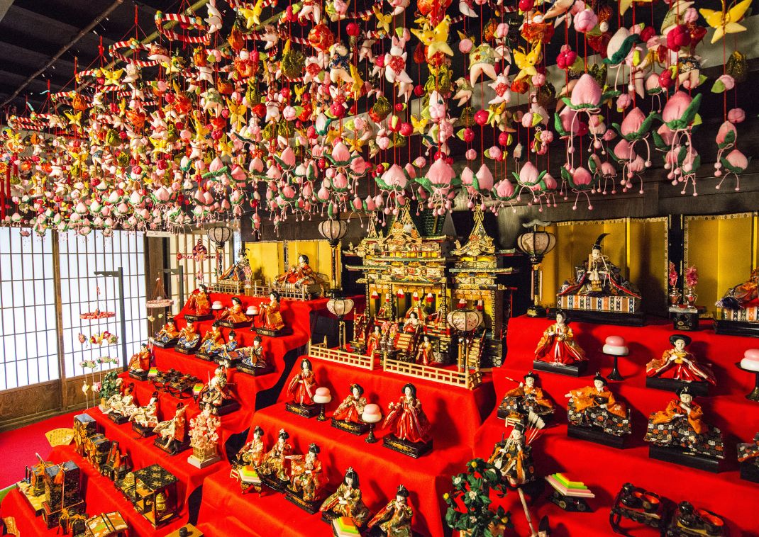 Poupées exposées sur un fond rouge dans le cadre du festival Hinamatsuri