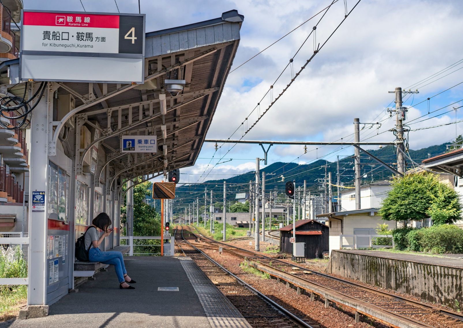 Jeune femme sur son téléphone portable sur le quai d’une gare à Kyoto, Japon