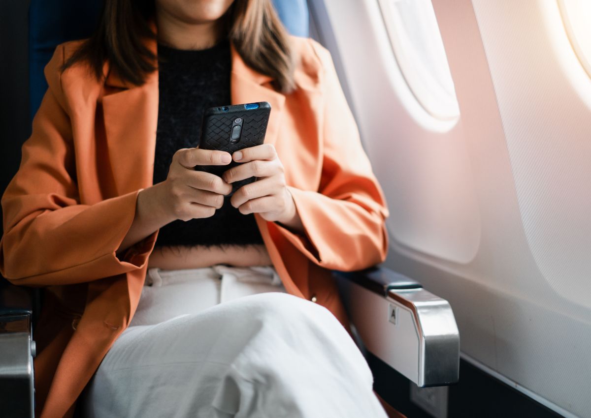 Jeune femme scrollant sur son téléphone portable dans l’avion