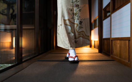 Femme en kimono marchant dans un ryokan traditionnel avec tatamis et portes shoji