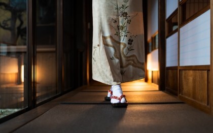 Femme en kimono marchant dans un ryokan traditionnel avec tatamis et portes shoji