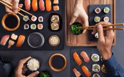 Sushis assortis (nigiri, sashimi et rouleaux) partagés et dégustés à l'aide de baguettes.