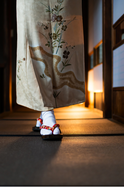 Femme en kimono marchant dans un ryokan traditionnel avec tatamis et portes shoji