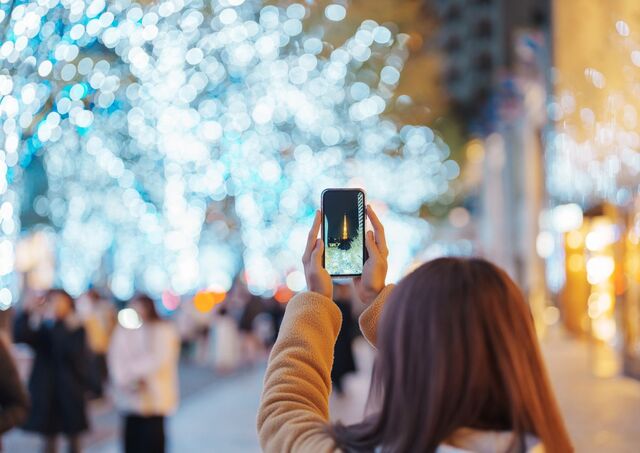 Jeune femme prenant une photo de la Tokyo Tower au milieu des illuminations de Noël à Radversgi Hills, Tokyo, Japon