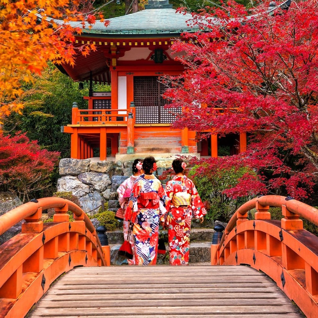 Trois femmes en kimono traversant un pont japonais dans un paysage d’automne