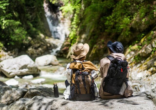 Couple de randonneurs assis devant un cours d’eau dans une forêt au Japon