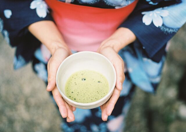 Geisha en kimono tenant une tasse de matcha