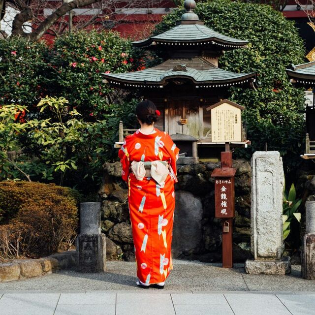 Femme en tenue traditionnelle japonaise près d'un sanctuaire dans un jardin au Japon