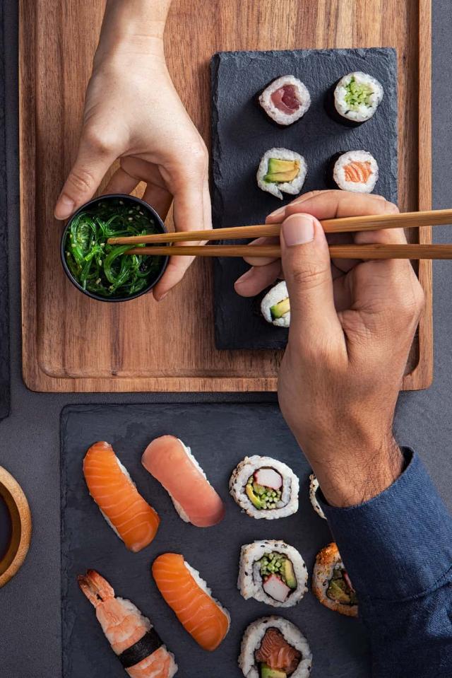 Sushis assortis (nigiri, sashimi et rouleaux) partagés et dégustés à l'aide de baguettes.